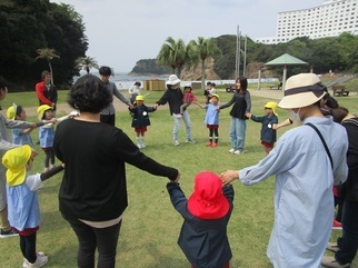 園児たちとその家族 みんなで手をつないで遊んでいる写真