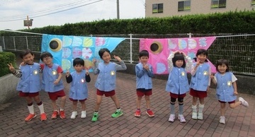 園児たちがみんなで作った鯉のぼりと一緒に記念撮影をしている写真