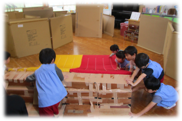 子ども達が力を合わせて大きなすべり台を移動している写真