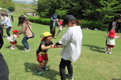 芝生の上で子どもと大人が一人ずつペアになりながら手を繋いでいる写真