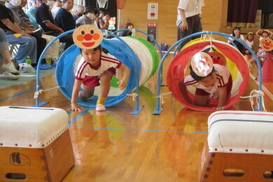 アンパンマンの顔が設置された筒の布の中を園児たちがくぐっている写真