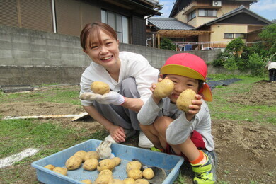 親子で収穫したじゃがいもを見て喜んでいる写真