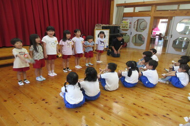 園児たちが体育座りをして小学生たちのお話を聞いている写真