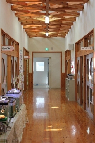 木目の床が敷かれている幼稚園の廊下の写真