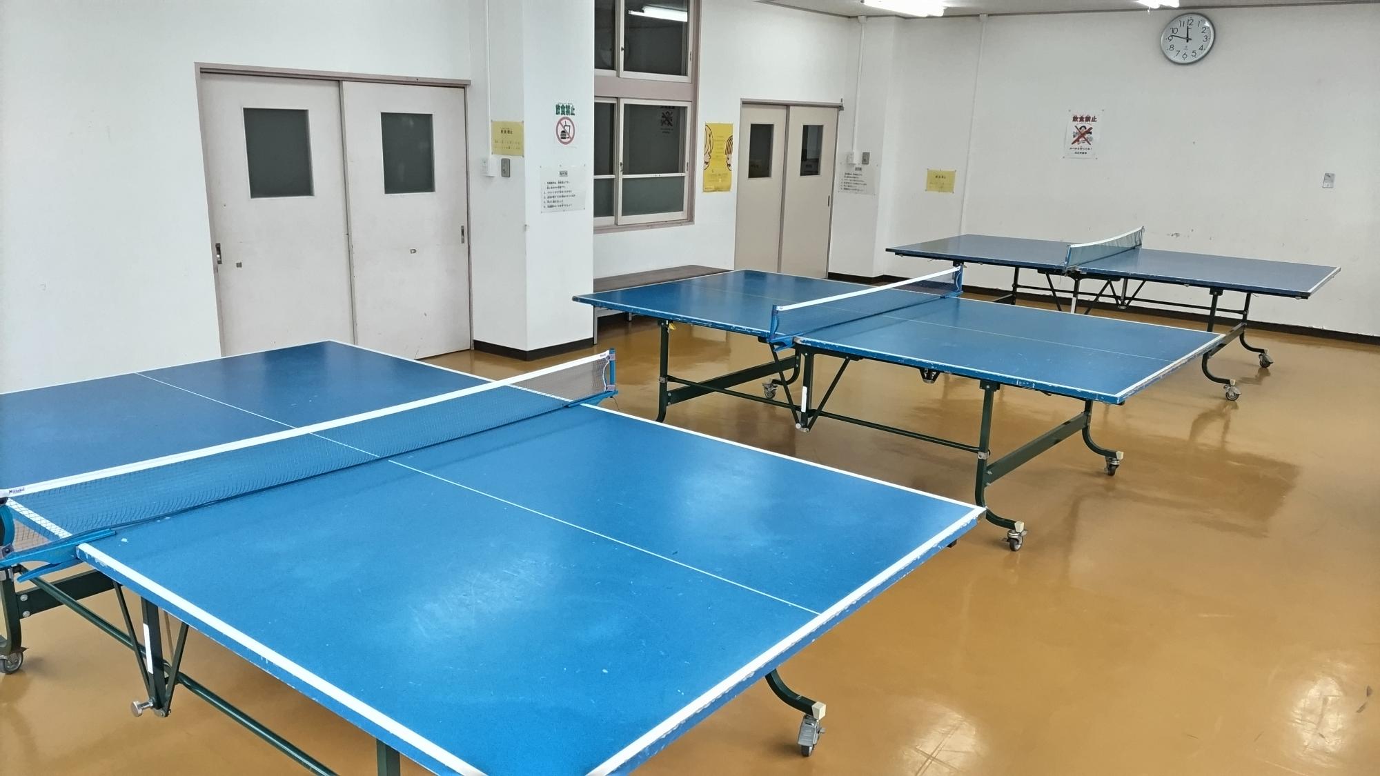 クッションフロアの床の上に卓球台が3台並べて置かれている写真