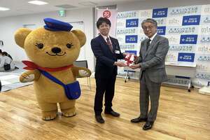 一番左に、くまの着ぐるみ、中央にスーツ姿男性2人の市長が、手紙を手渡している写真