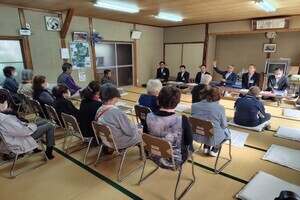 和室で前方に数名の人が横一列に並んで座り、その手前で参加者たちが話を聞いている写真