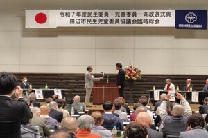 壇上で書状を受け渡している状況を見ている人たちの写真