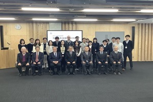 会議室の前方で、発表会の参加者たちが、数列に並んで集合している写真