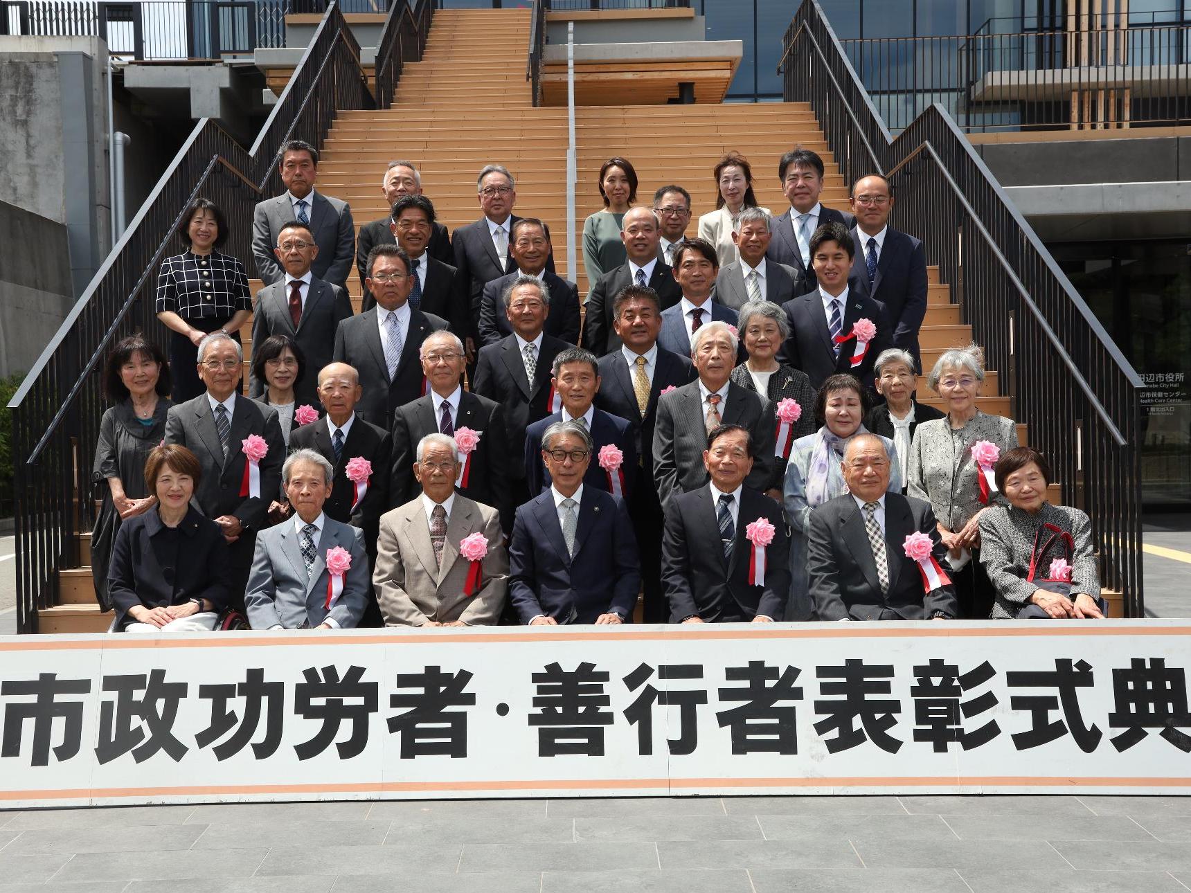市役所の階段を使って40人ほどの人々が記念撮影をしている写真
