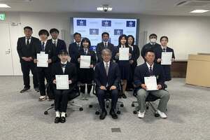 前方の椅子にスーツ姿の男性が座り、その後ろに高校生たちが数列に分かれて整列し、全員で正面を向いている写真