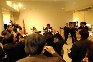 前方の大きな画面を挟んで左右のテーブルに登壇者たちが分かれて座りシンポジウムを行っている写真