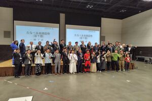 前列と後列の2列に並んだ参加者たちが、力強く拳を突き出してポーズをとっている集合写真