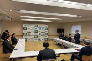 会場の前方に設置された長い机に、男性が横一列に並んで座っている写真